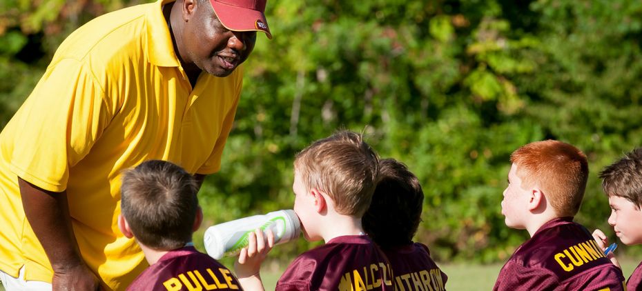 Coach teaching kids how to play soccer